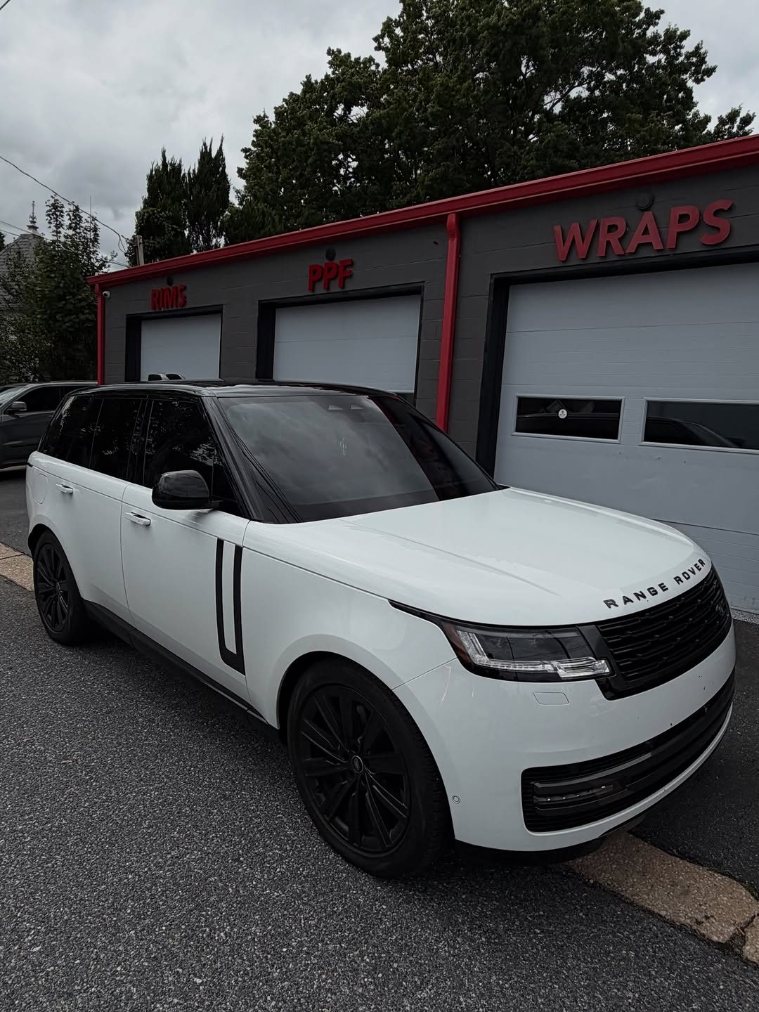 White Range Rover with dark tinted windows outside the shop
