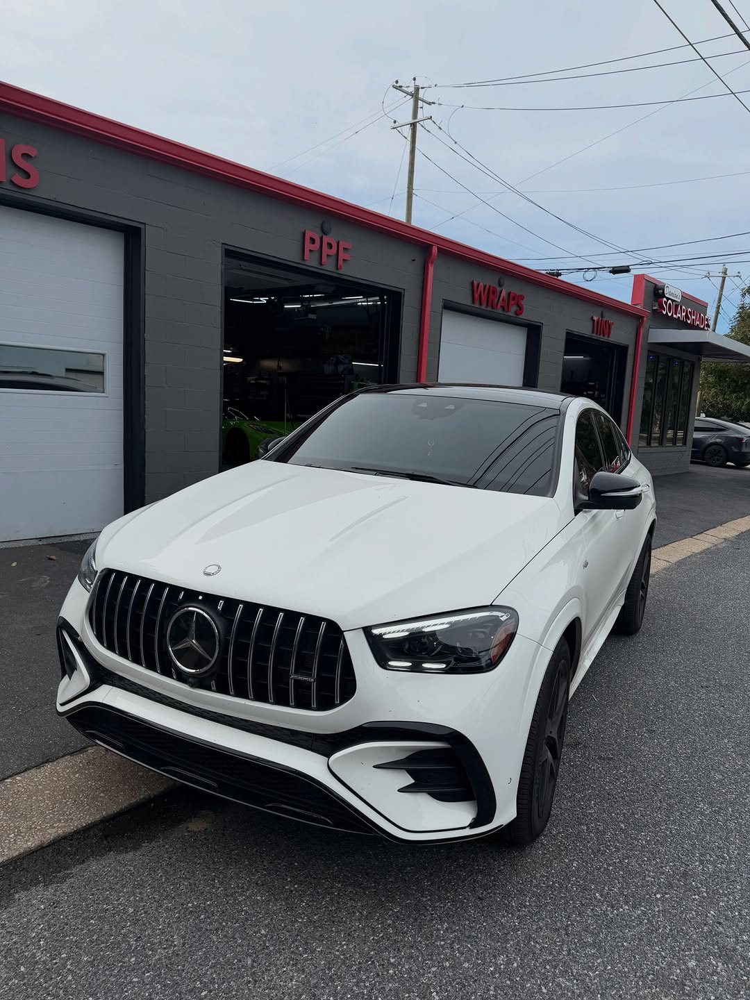 White Mercedes-AMG GLE 53 coupe with tinted windows outside the shop