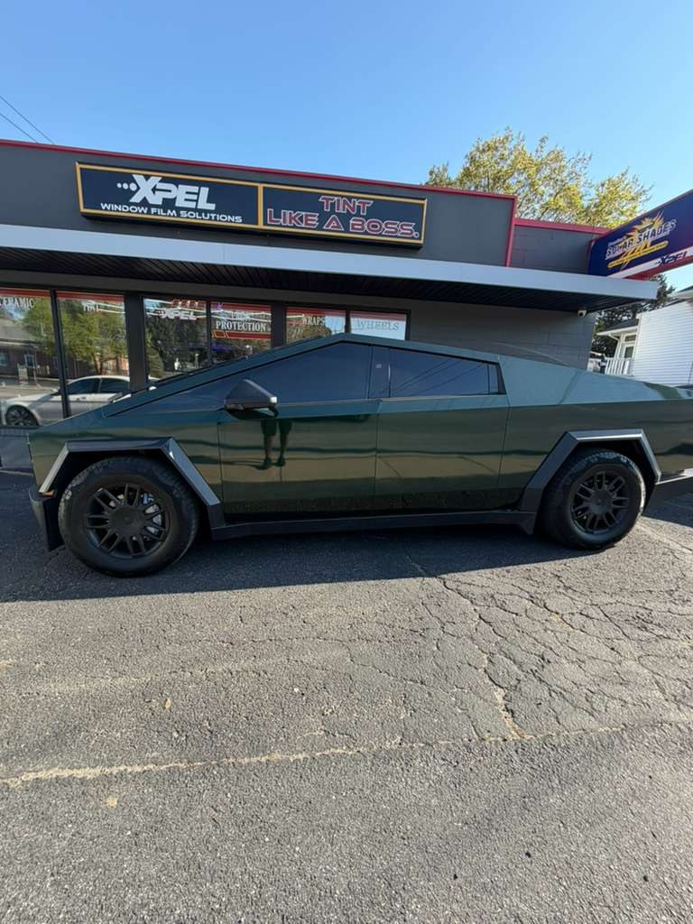 Tesla Cybertruck in dark green in front of the XPEL storefront