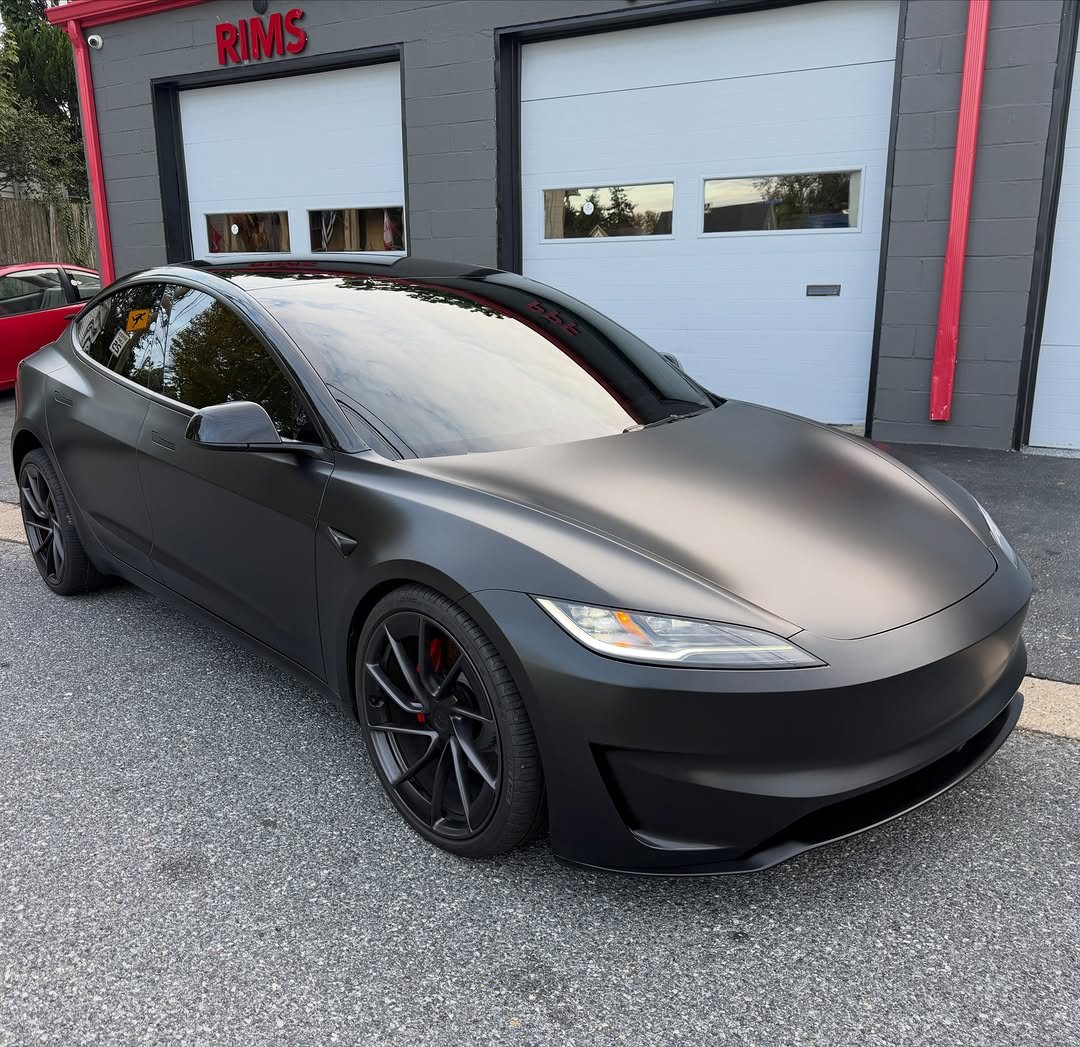 Tesla in satin PPF, front three-quarter view outside the Rims bay
