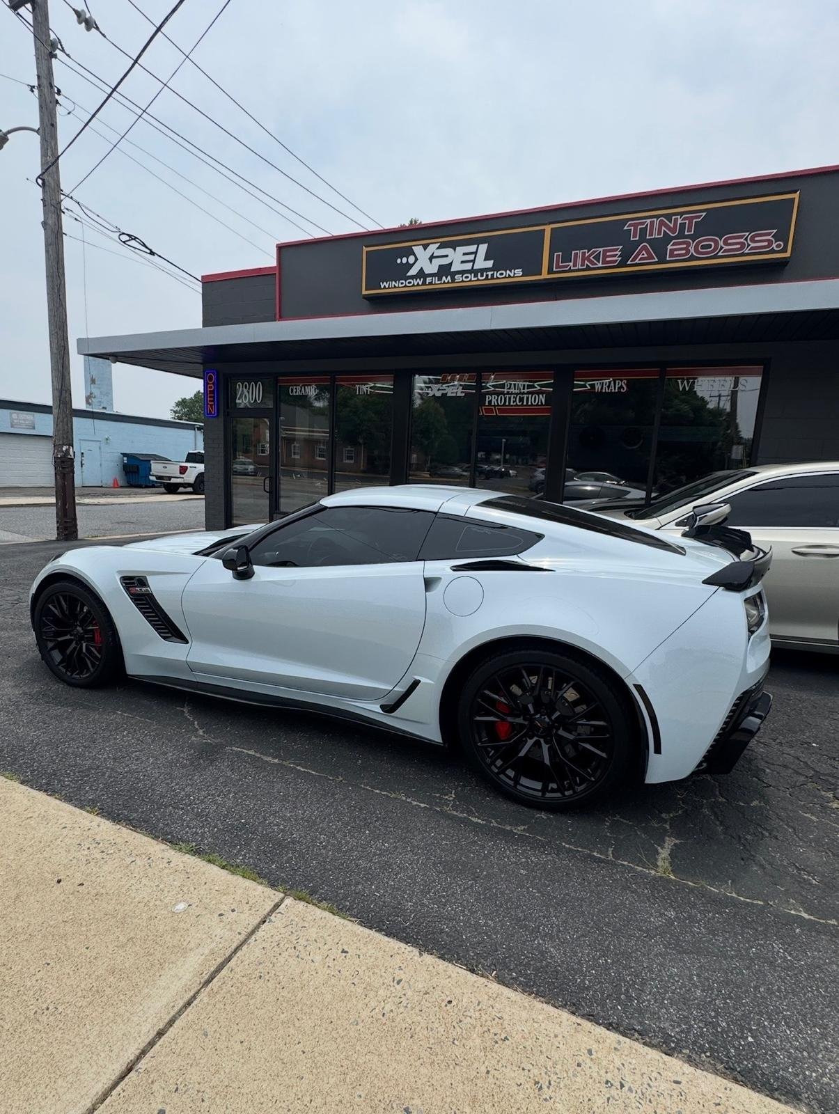White Corvette Z06 with tinted windows and black wheels outside the XPEL storefront