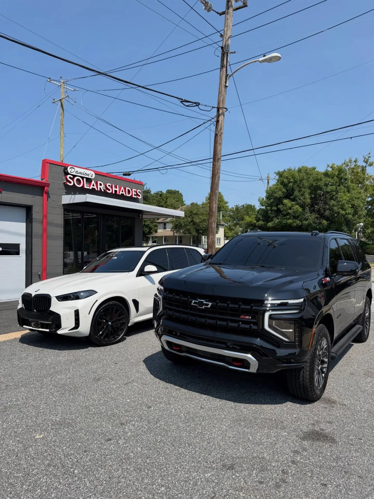White BMW X5 and black Chevrolet Tahoe Z71 with tinted windows outside Damion's Solar Shades